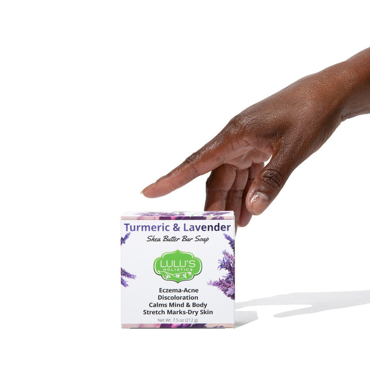 An outstretched arm holding a box of Lulu's Holistics Turmeric and Lavender Shea Butter Bar Soap. Buy this natural skin solution online to clear acne, soothe eczema, and fade dark spots globally.