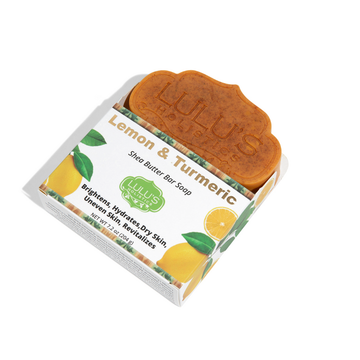 Angled product view of Lulu's Holistics Lemon & Turmeric Shea Butter Bar Soap partially unboxed, displaying the embossed brand logo on the orange-brown bar alongside its white and yellow packaging.