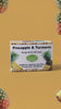 Cinematic motion video showing three floating boxes of Lulu's Holistics Pineapple and Turmeric Mango Butter Bar Soap with moving shadows and drifting fresh cut pineapples on a yellow background